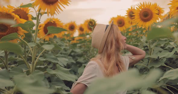 Nice Girl in a Hat Peeks Out in the Sunflowers Looks Into the Distance