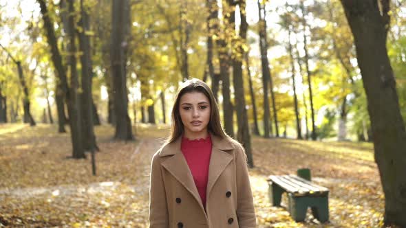 Brunette Stands in Sunny Autumn Park Admires the Nature and Looks at Camera alt