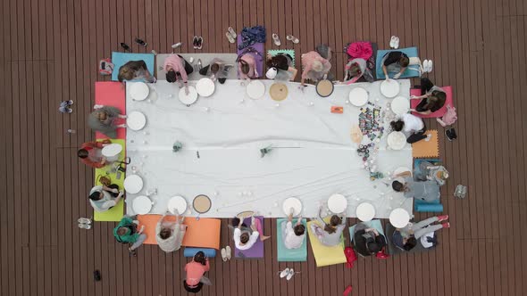 Aerial View of a Group of Women and Children Engaged in Creativity on a Wooden Terrace in the Open