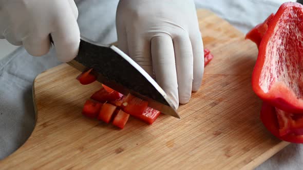 Chef Cuts Red Bell Pepper with a Knife on a Cutting Board
