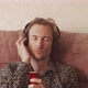Young Man Thoughtfully Browsing Mp3 Player And Listening To Music On The Sofa - VideoHive Item for Sale