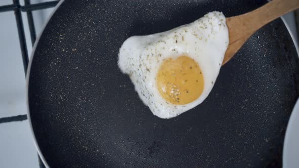 Egg with Spices is Placed on a White Plate with a Wooden Spatula Close Up alt