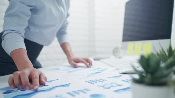 Businesswoman analysing and looking at diagrams on documents in workplace