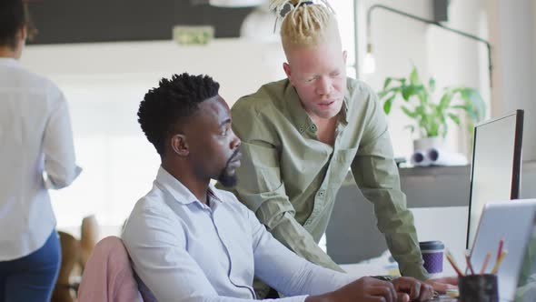 Diverse business people discussing with laptop in creative office alt