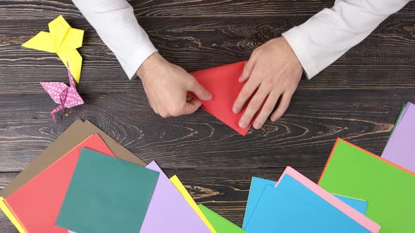 Male Hands Folding Red Paper Sheet. alt