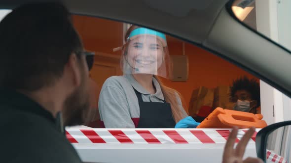 Man Driver in Car Ordering Takeaway Meal at Drive Thru Counter of Fast Food Restaurant alt