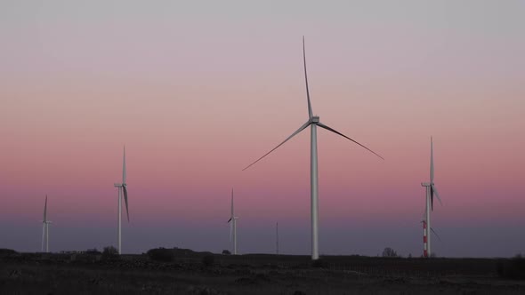 Wind turbines rotating at sundown spinning at dusk