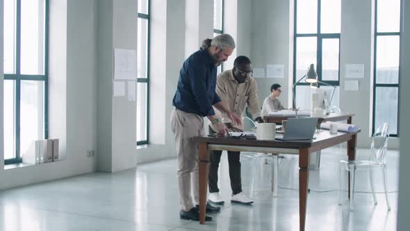 Multiethnic Male Architects Discussing Project in Office alt