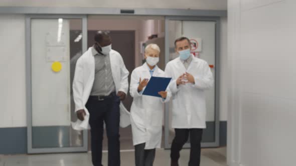 Team of Physicians Wearing Lab Coat and Protective Mask Discussing Patient Medical Test alt