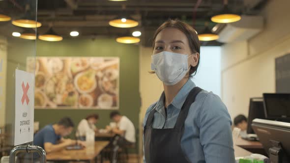 Portrait of Young woman restaurant owner wearing protective mask stand in in front of restaurant