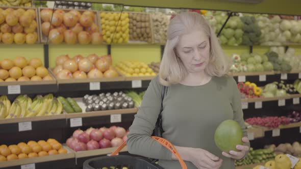 Portrait of Happy Confident Caucasian Woman Buying Fruits in Grocery. Senior Blond Housewife Putting alt