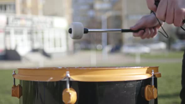 Drumsticks in Male Hands Beat the Big Drum on the Street