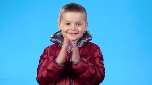 Child Looking at the Camera, Smiling and Clapping His Hands. alt