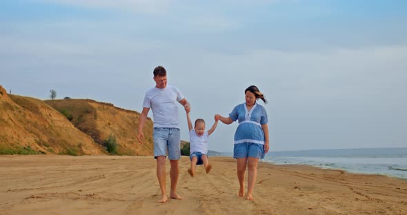 Pregnant Woman with Her Husband and Child Walks Along the Seashore