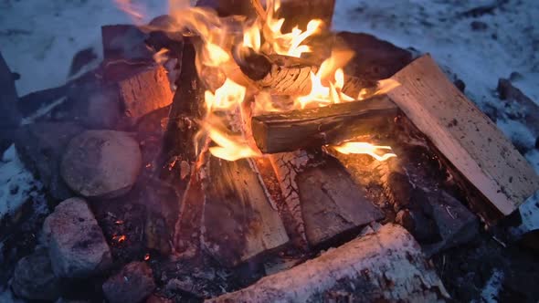 Logs burning in a outdoor campfire, surrounded by snow, on a windy evening in Lapland, Finland alt