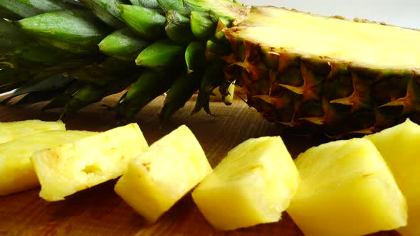 Pieces of pineapple on a cutting wooden board. alt