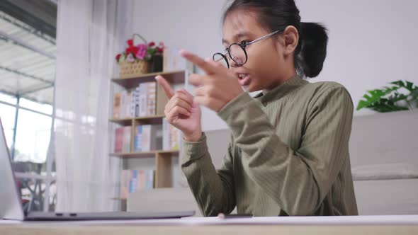 Asian girl studying online and taking video call on laptop in living room alt