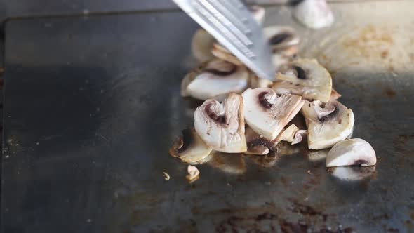 The chef prepares mushrooms on the stove and mixes them