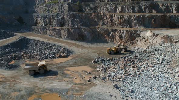 Large Vehicles Working Around a Large Open Quarry alt