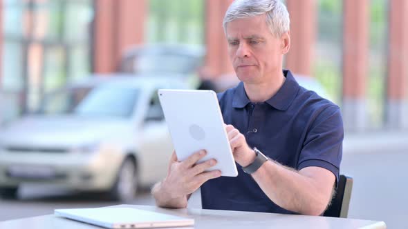 Outdoor Focused Middle Aged Businessman Working on Tablet alt