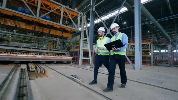 Two Industrial Workers Are Walking Through the Factory Facility alt