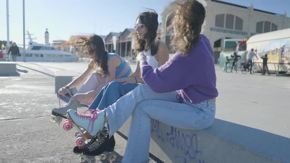 Side View of Three Girls Tying Roller Skates with Wind in Their Hair alt