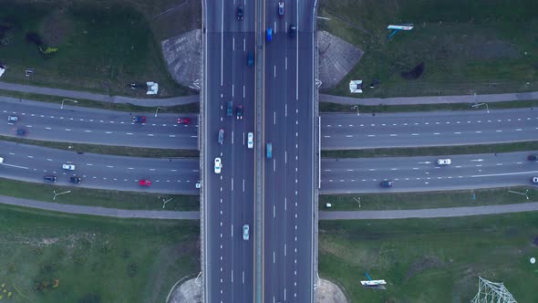 Aerial drone view of highway multi-level junction road with moving car at sunset