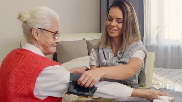 Female Caregiver Taking Blood Pressure of Senior Woman