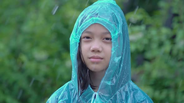 Slow motion Asian girl wearing blue raincoats playing splashing in the outdoors