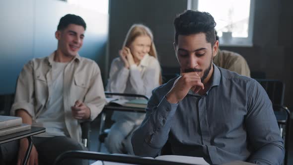 Sad Frustrated Arab Student Sitting in Class at Desk Alone Suffering From Mistreatment By Classmates alt