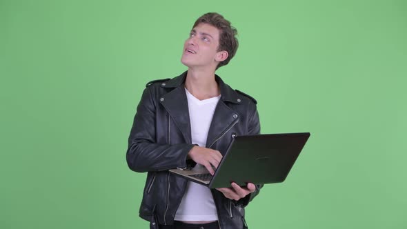Happy Young Rebellious Man Thinking While Using Laptop alt