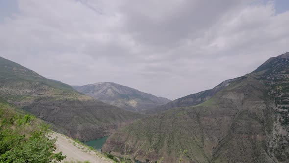 River in rocky mountains on background of cloudy sky alt