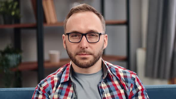 Closeup Portrait of Modern Bearded Male in Eyeglasses and Checked Shirt Sitting on Couch alt