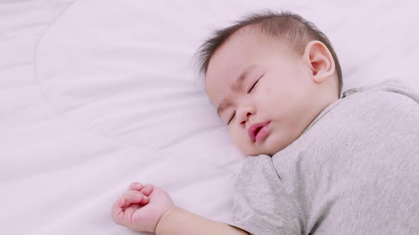 Sleeping cute baby girl on bed during the daytime. Protection of children. alt