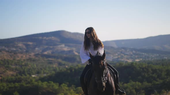 Portrait of Gorgeous Young Woman Sitting on Brown Horse in Sunny Mountains alt