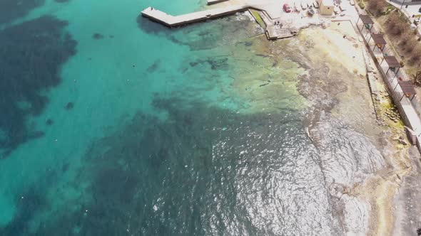 Bird's eye view of Pier extending over Clear Mediterranean water on the shores of Sliema, in Malta alt
