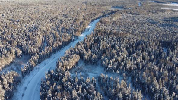 Aerial View From a Drone of a Road in the Middle of Snowcovered Trees and Snowcovered Forest on a