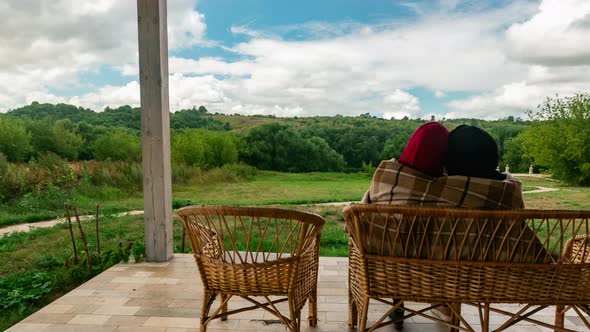 Family Couple Rests in Village House Sitting on Bench and Hugging in Timelapse alt