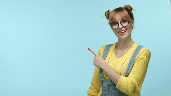 Cheerful Girl with Cute Bangs Wearing Glasses and Yellow Sweater Pointing Finger at Upper Left