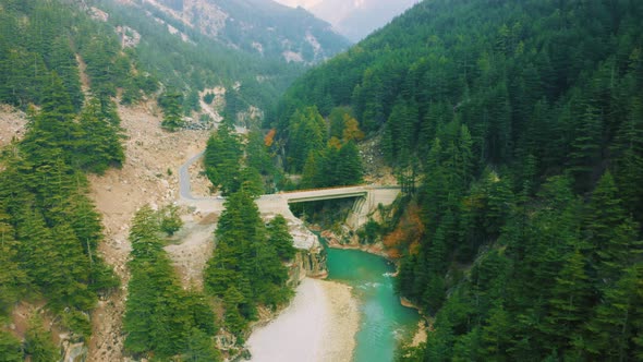 Aerial View of bridge above the Bhagirathi river surrounded by green pine forest in Harshil