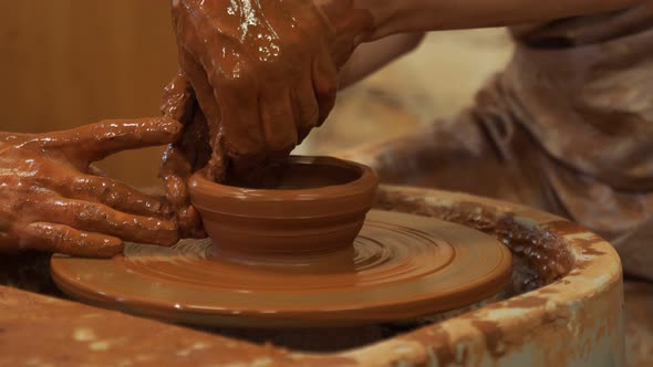 Hands of the Skilled Master Potter and Woman Hands Training of the Woman to Production of Pottery on alt