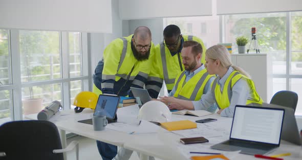 Professional Diverse Engineers Discussing New Project Using Laptop in Office alt