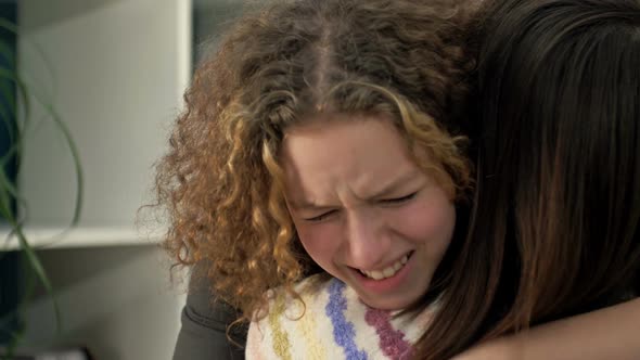 Teenage Girl is Crying Bitterly on the Shoulder of Her Mother or Friend