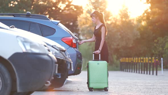 Young Female Driver Loading Luggage Suitcase Bag Inside Her Car alt