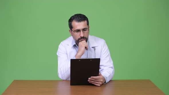 Handsome Persian Bearded Man Doctor Reading Clipboard and Thinking