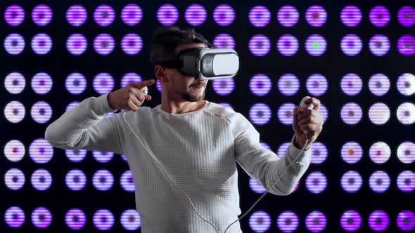 Man in Virtual Reality Glasses Plays Game of Joysticks Shooting Arrows From Bow