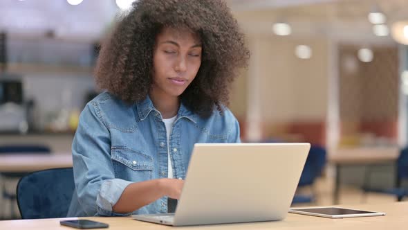 Young African Woman with Laptop Smiling at Camera at Work  alt