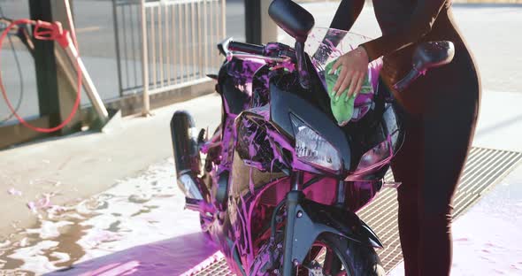 Woman in Tight Black Wear Polishing with Cloth Expensive Modern Iron Horse from Foamy Solution alt