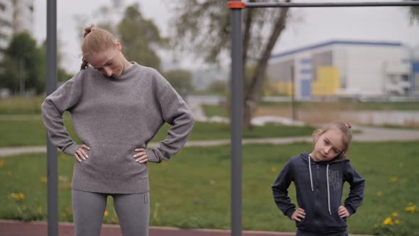  Mother and Daughter Doing Exercises on Open Air Sport Playground alt