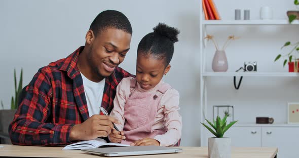 Afro American Father Teaches Little Daughter to Write Letters Makes Notes in Notebook Child Learns alt